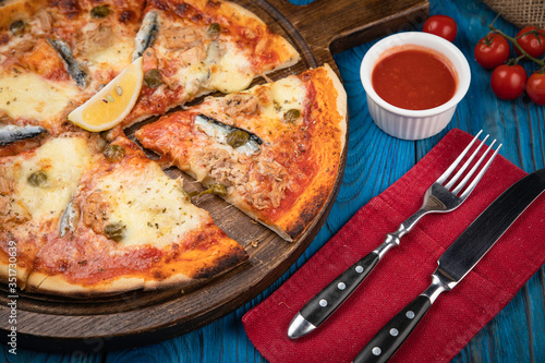 Italian pizza with fish on brown background