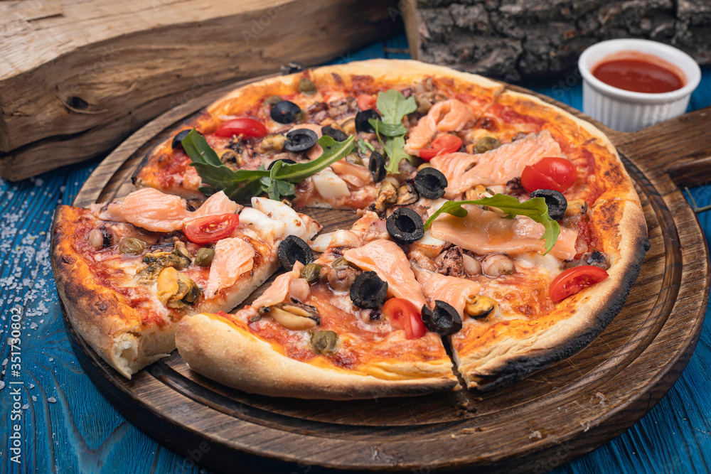 Italian pizza with salmon and olives on blue background