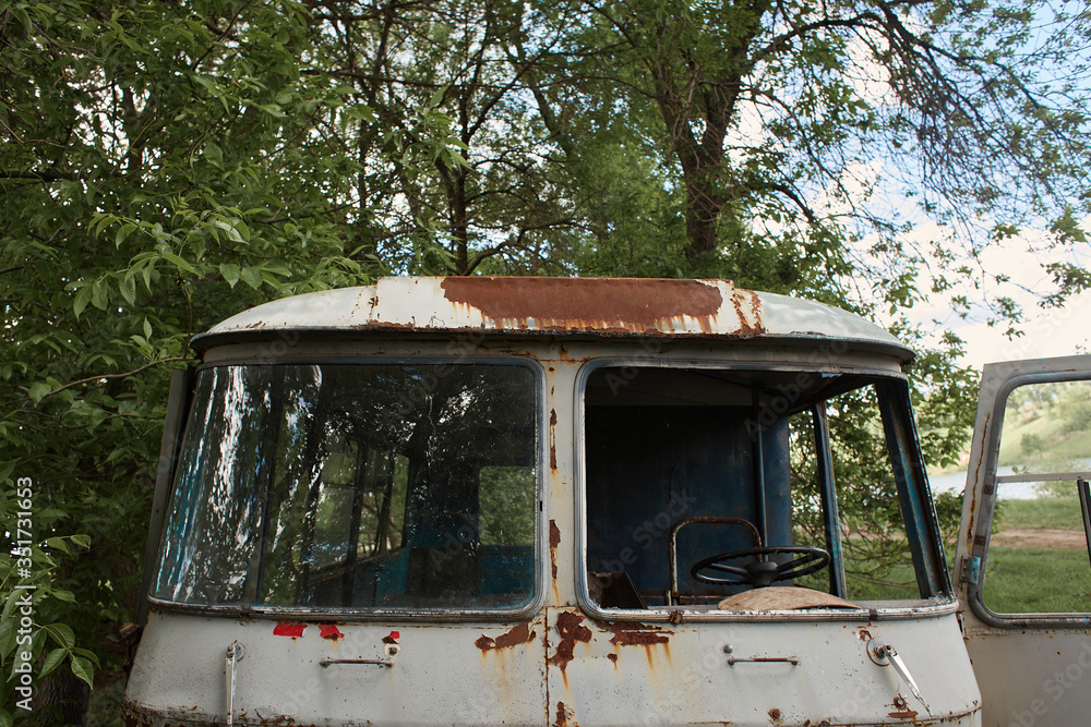 Old abandoned wrecked gray bus in the field. Front side. The driver's seat close-up. Full frame.