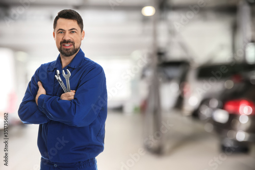 Professional mechanic with wrenches at tire shop. Space for text