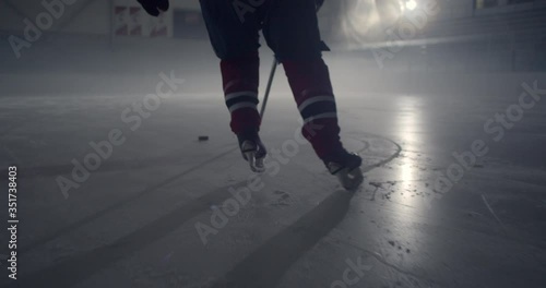 Close up of skates in dramatically lit hockey rink skating and stick handling. Rink is filled with cool mist, fog in the air, 4K