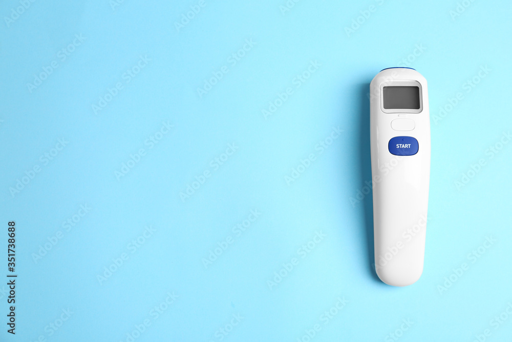 Modern non-contact infrared thermometer on light blue background, top view. Space for text - obrazy, fototapety, plakaty 