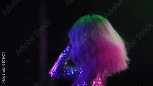 Rear view African-American dancing in a dark room with neon lighting. girl with blond hair dancing in a club enjoying music. Neon concept. Prores 422. 