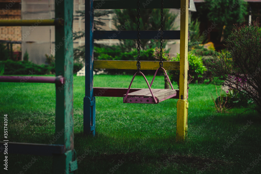 wooden swing on chains in the garden on a background of greenery wooden swing on chains in the garden on a background of greenery