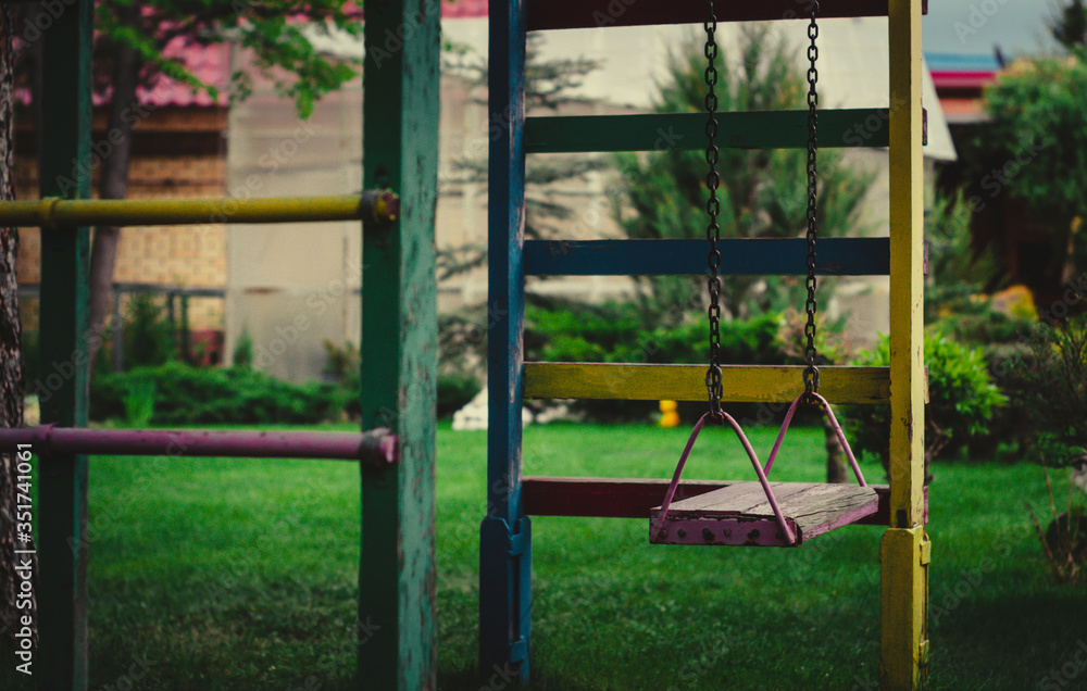 wooden swing on chains in the garden on a background of greenery