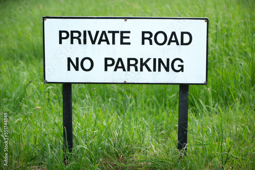 Private Road No Parking sign on grass field.