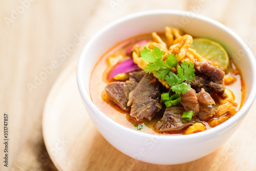 Northern Thai food (Khao Soi), spicy curry noodles soup with coconut milk and beef in a bowl