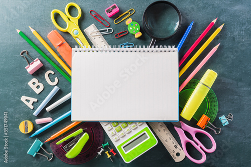 Education or back to school Concept. Top view of Colorful school supplies with books, color pencils, calculator, pen cutter clips chalkboard background. Flat lay.