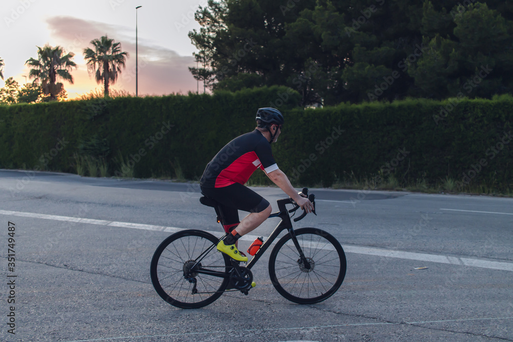 Cyclist ride, dressed up with red and black cloths on country roads on a evening in Spain. Cyclist ride, dressed up with red and black cloths on country roads on a evening in Spain.