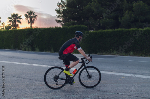 Cyclist ride, dressed up with red and black cloths on country roads on a evening in Spain.