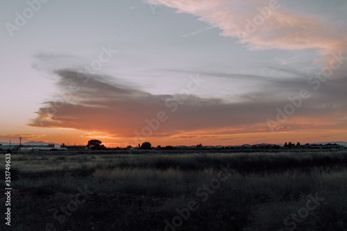 Natural Sunset Sunrise Over Field Or Meadow. Bright Dramatic Sky And Dark Ground. Countryside Landscape Under Scenic Colorful Sky At Sunset Dawn Sunrise. Sun Over Skyline, Horizon. Warm Colours. © viajeroscreativos