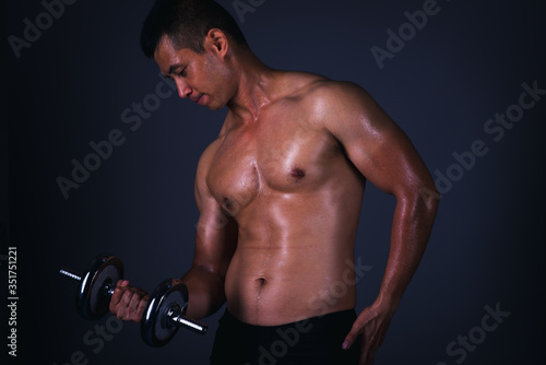 Muscular model Asian young man on Gray background. Portrait of strong brutal guy with trendy hairstyle. Sexy naked torso  six pack abs. Male flexing his muscles. Sport workout bodybuilding concept.
