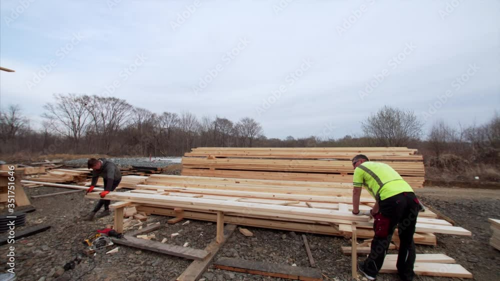 Time lapse of two builders cutting long wooden planks with circular saw. Frame house building site Time lapse of two builders cutting long wooden planks with circular saw. Frame house building site