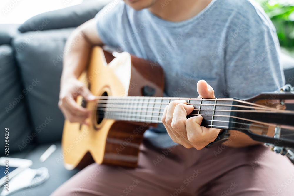 Fototapeta premium Working from home playing guitar learning online education video free time spending activity, self isolation quarantine lockdown staying safe in house living room protection from coronavirus covid-19