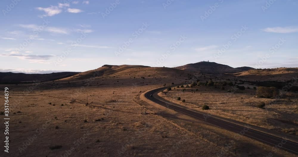 Van driving around corner with landscape beautifully lit at sunset with observatory in the distance Van driving around corner with landscape beautifully lit at sunset with observatory in the distance