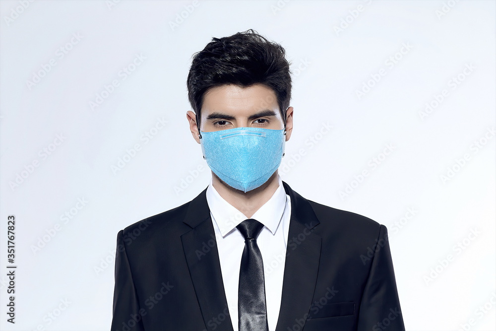 Young businessman wearing a blue N95 medical-surgical mask against a white background Young businessman wearing a blue N95 medical-surgical mask against a white background
