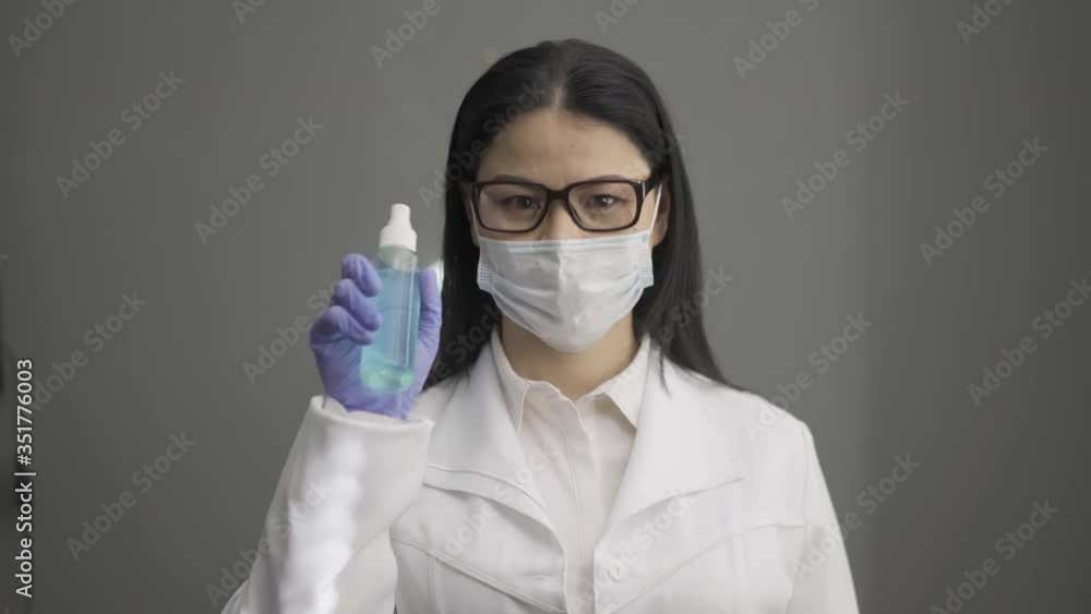 Woman wearing glasses taking antibacterial liquid and cleanse gloves showing it as a tutorial on the camera. prores 422. Woman wearing glasses taking antibacterial liquid and cleanse gloves showing it as a tutorial on the camera. prores 422.