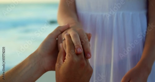 Man putting ring on woman finger at beach photo