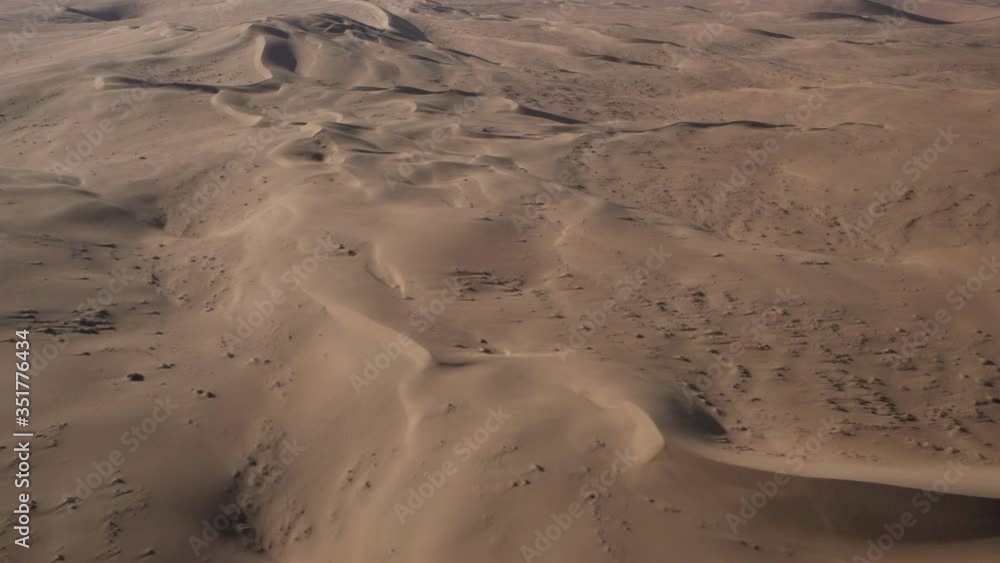 Aerial shot of desert area during sunny day, airplane moving over sand dunes at remote location - Sossusvlei, Namibia Aerial shot of desert area during sunny day, airplane moving over sand dunes at remote location - Sossusvlei, Namibia