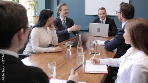 Group of young freelancers are sitting in a conference or board room and brainstorming new ideas for developing their project. Business people with laptops on desk working descussing ideas. Prores 422