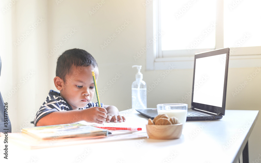 The little Asian boy studying online at home. Concept of online learning. The little Asian boy studying online at home. Concept of online learning.