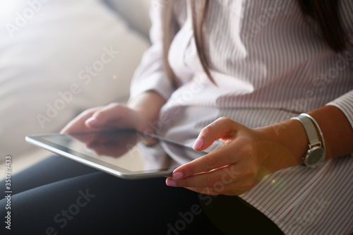 female hand holds tablet in home setting while