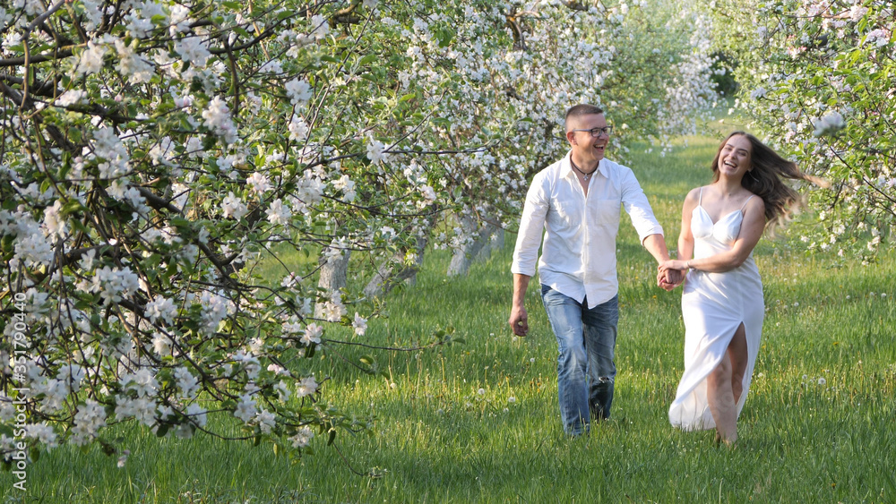 Obraz premium young guy and girl in blooming apple trees in the garden