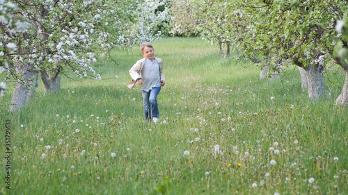 boy on the grass near blooming apple trees in the garden