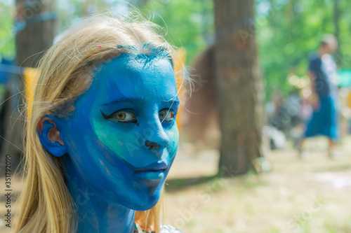 The girl's face is completely painted blue with aqua-grime. Festive preparation. photo