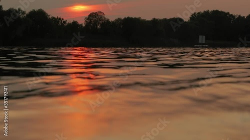 Rippling water surface gleaming in sunset light, calm nature scene, sunlight reflection in 4k 60 fps photo