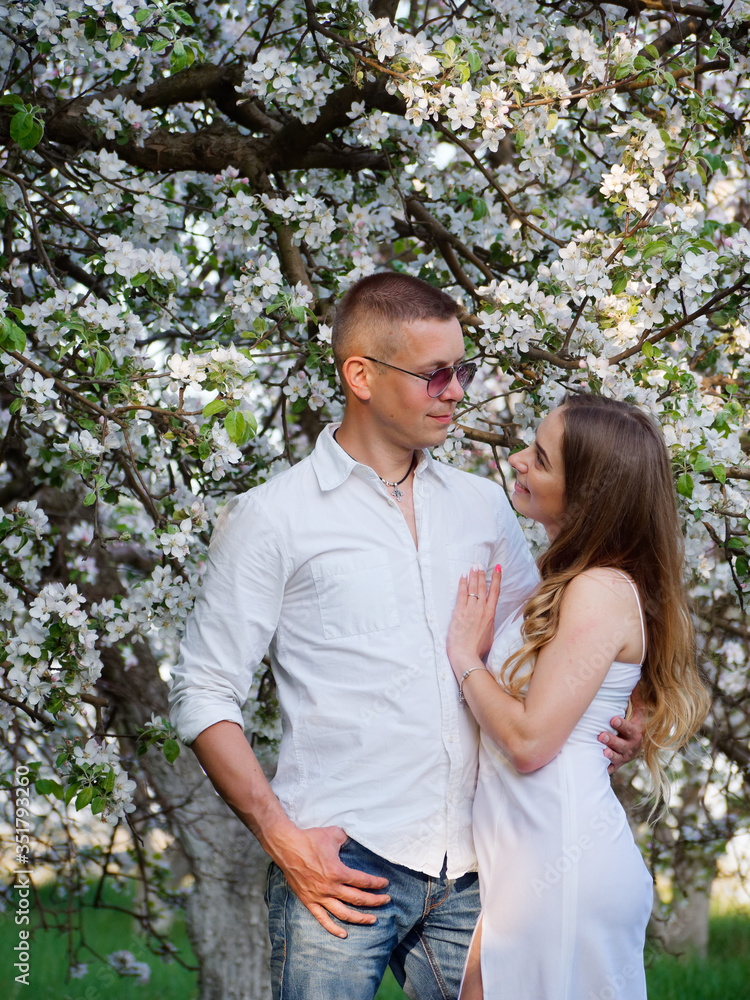 young guy and girl in blooming apple trees in the garden young guy and girl in blooming apple trees in the garden