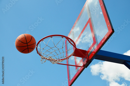 a basketball ball flies into a ring on an open field against the sky © BetterPhoto