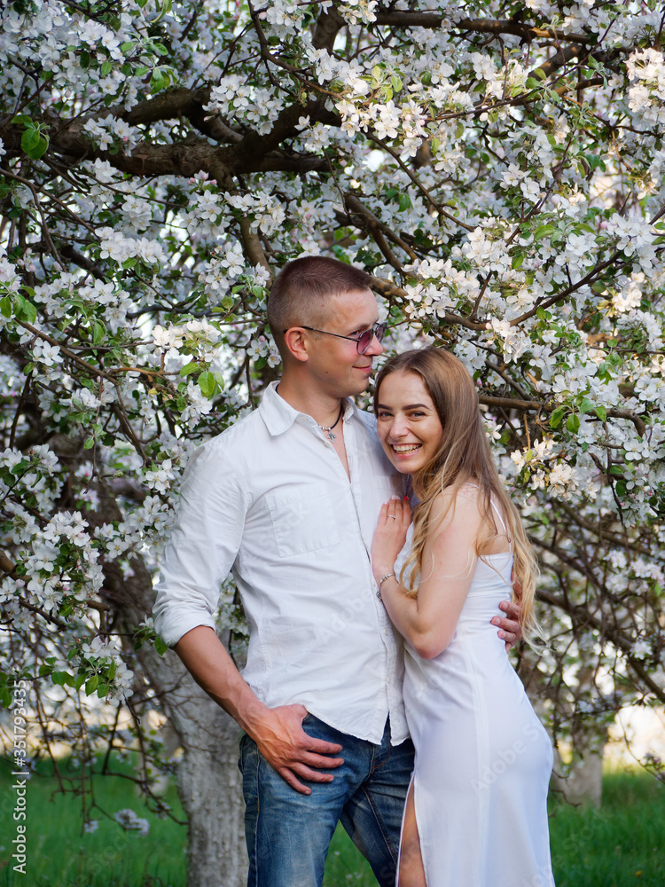 young guy and girl in blooming apple trees in the garden young guy and girl in blooming apple trees in the garden