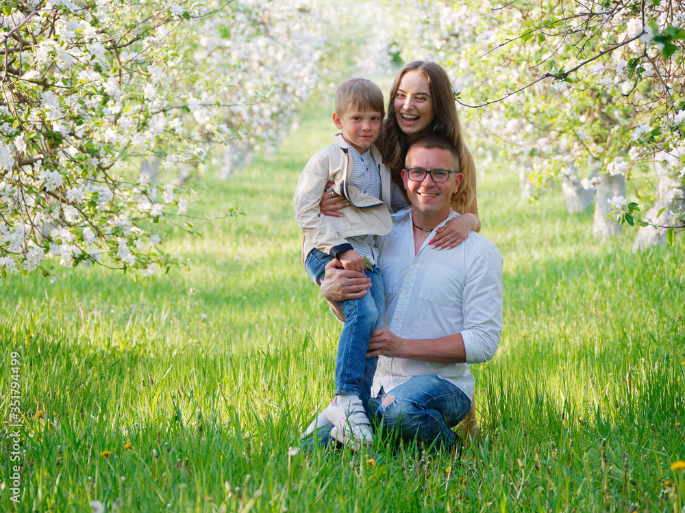 family with a child in blooming apple trees in the garden family with a child in blooming apple trees in the garden