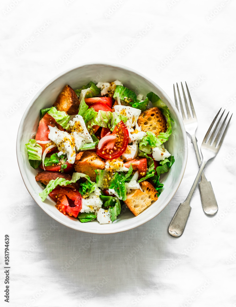 Simple salad with fresh tomatoes, crispy ciabatta, mozzarella cheese, green salad with olive oil, mustard, lemon dressing on a light background, top view Simple salad with fresh tomatoes, crispy ciabatta, mozzarella cheese, green salad with olive oil, mustard, lemon dressing on a light background, top view