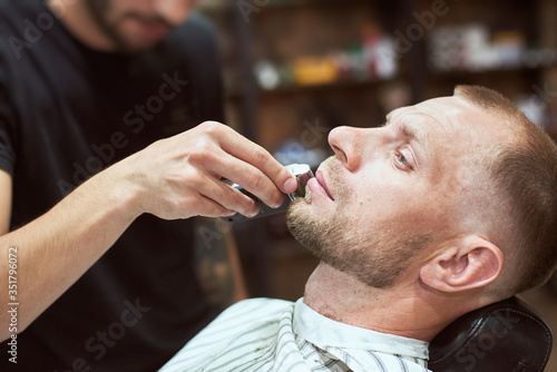 Unrecognizable blurred hairdresser is doing a perfect beard shape to his male client at barber shop, time to take care of oneself, relaxation © anatoliy_gleb