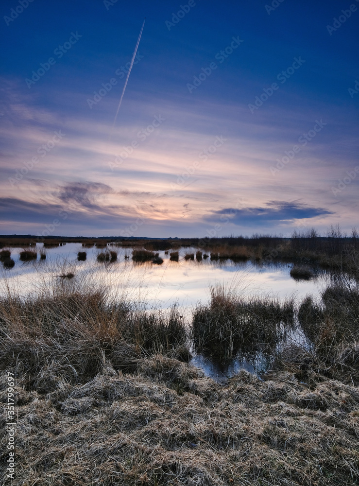 Obraz premium Colorful sky and colorful water in lake reflected in evening, focus on grass in foreground