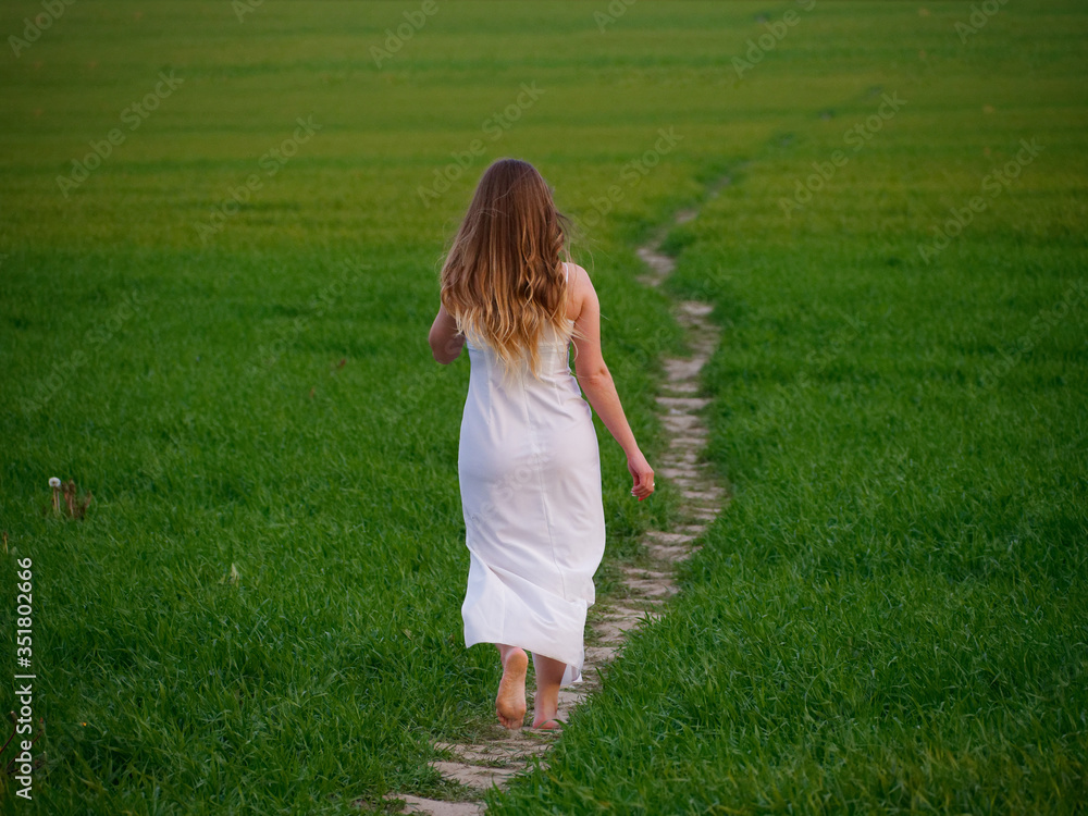 girl in a long white dress on a green field