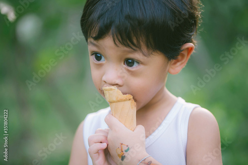 Asia boy he mouth aftertaste from eating chocolate ice cream  or chocolate dessert. A sweet-toothed child eat chocolate. Kid with dirty face eating ice cream. Cute toddler boy eating icecream.