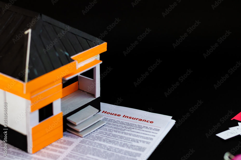 High angle shot of a house model with insurance papers below. High angle shot of a house model with insurance papers below.