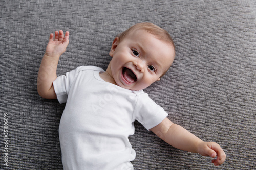Happy baby lying on grey couch