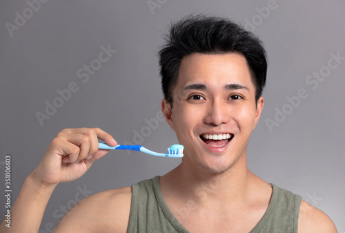  smiling asian young man with toothbrush . health and beauty concept