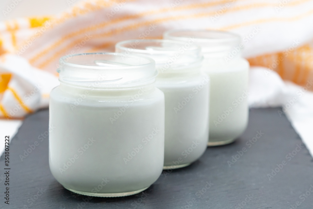 Three glasses of yogurt on a slate plate on a white background Three glasses of yogurt on a slate plate on a white background