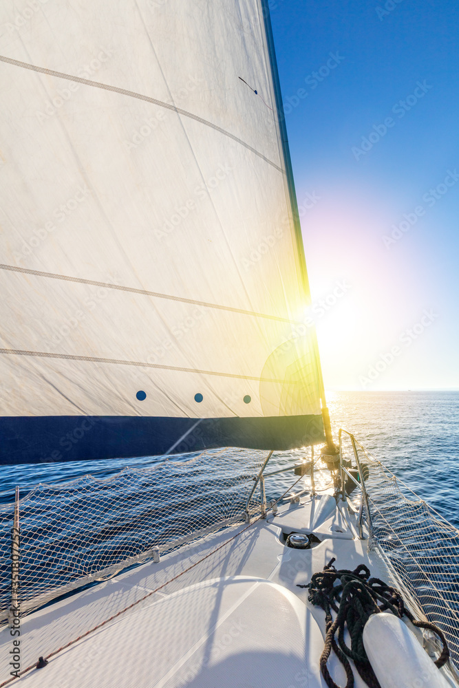 Obraz premium Sail boat yacht with set up sails gliding in open sea with sun