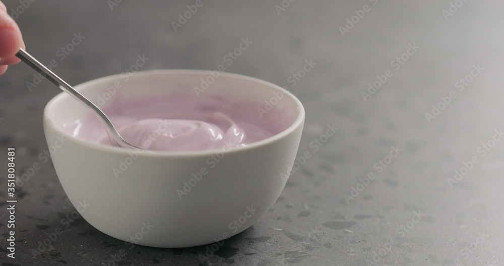 man hand scoops blueberry yogurt from white bowl with copy space man hand scoops blueberry yogurt from white bowl with copy space