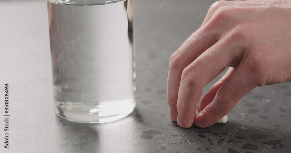man hand take white pills and glass of water from terrazzo countertop man hand take white pills and glass of water from terrazzo countertop