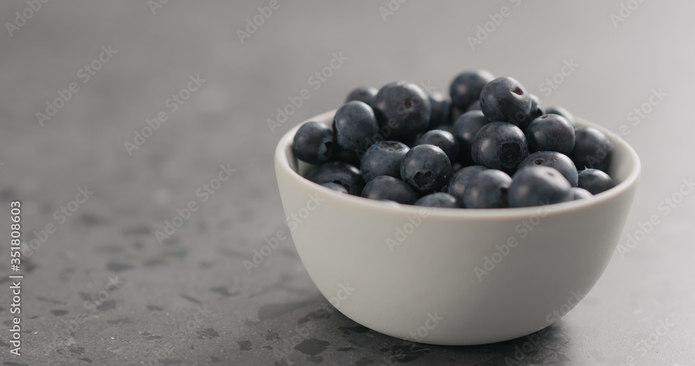 ripe blueberries in white bowl on concrete background with copy space ripe blueberries in white bowl on concrete background with copy space