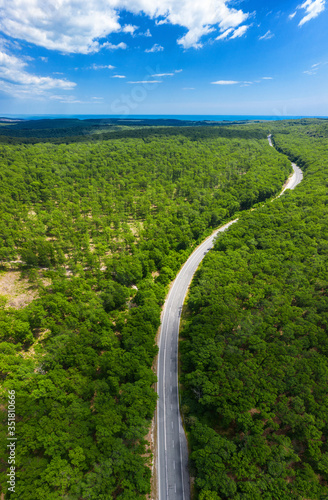 Aerial view of drone to road through green forest