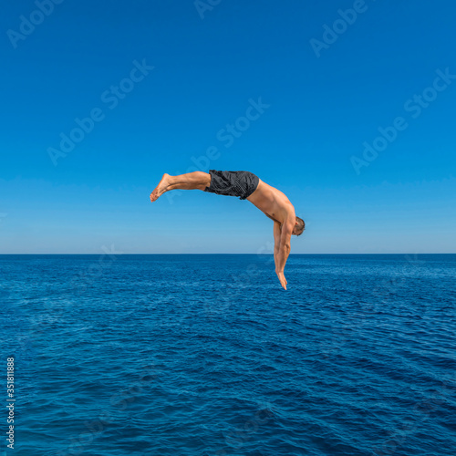 Fly after jump. Man jumping in blue sea water for dive. Summer fun lifestyle