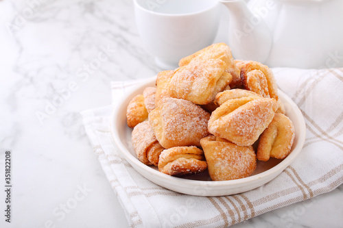 Freshly baked cottage cheese and sugar cookies (triangles, angles) in a marble background. Crow's feet.